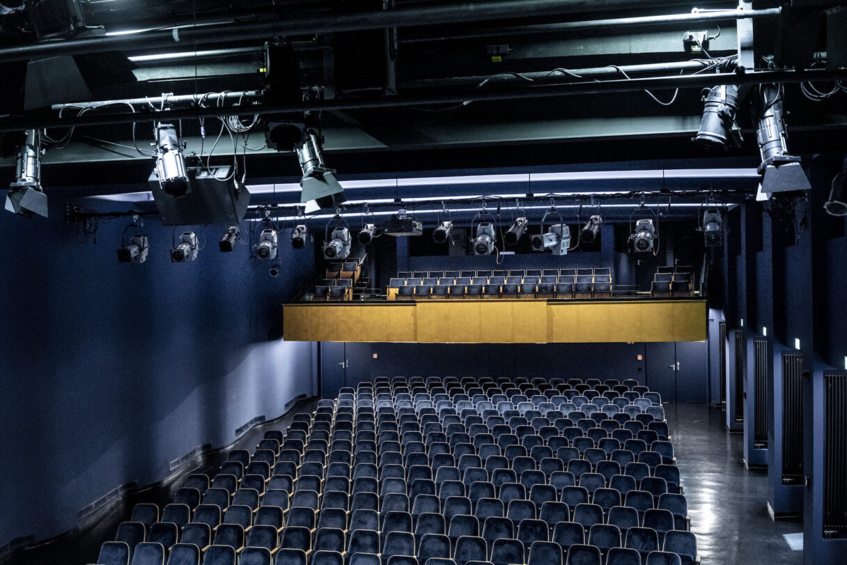 Dunkelblauer Zuschauersaal mit goldener Trib&uuml;ne. An der Decke einige Scheinwerfer.