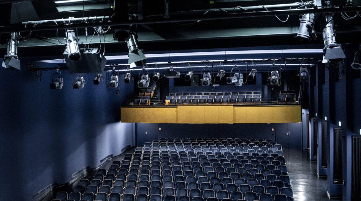 Dunkelblauer Zuschauersaal mit goldener Trib&uuml;ne. An der Decke einige Scheinwerfer.