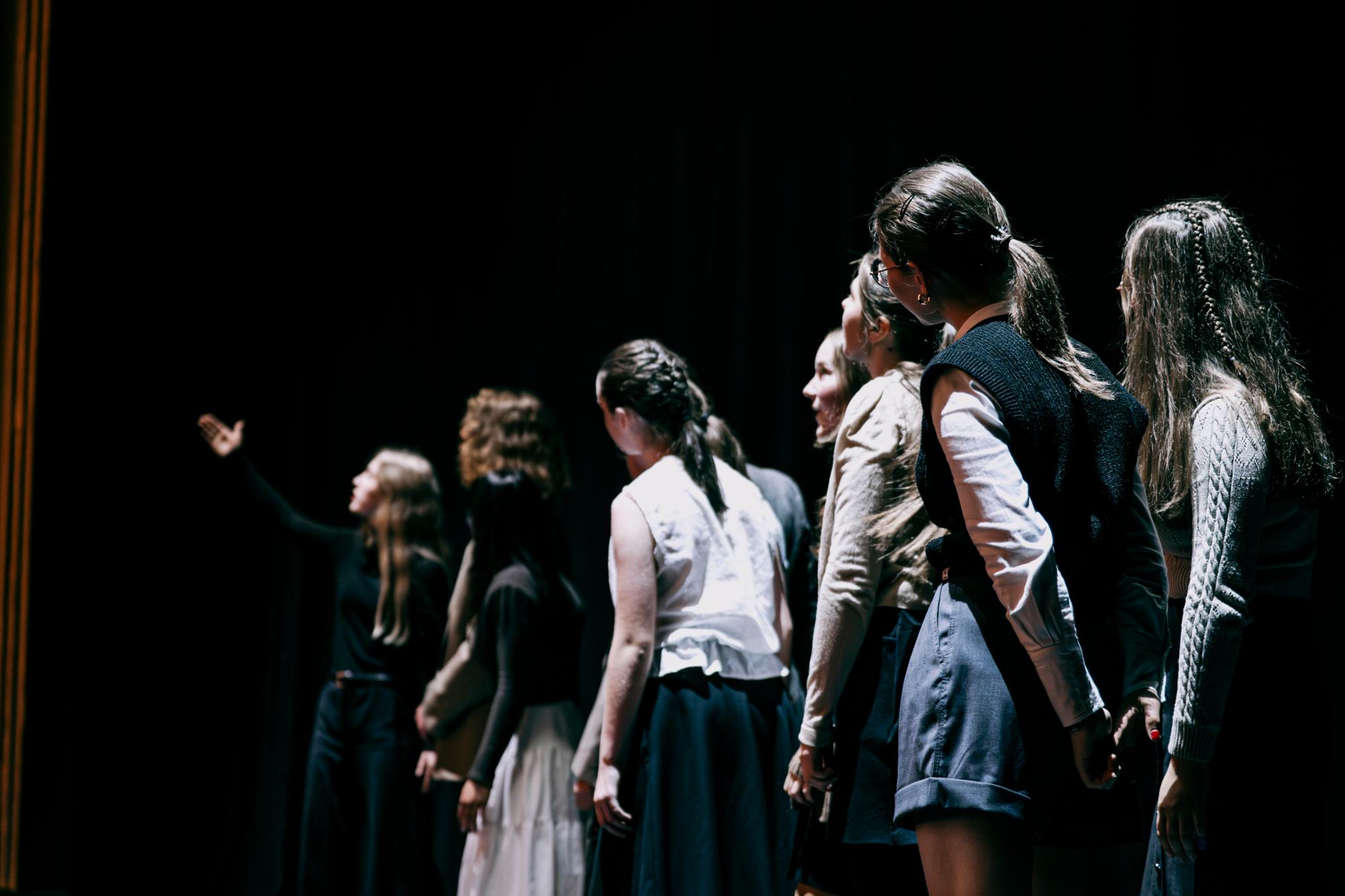 Eine Reisegruppe steht in einer Reihe und schaut zu der Gruppenleitung, welche mit dem Finger auf etwas zeigt.