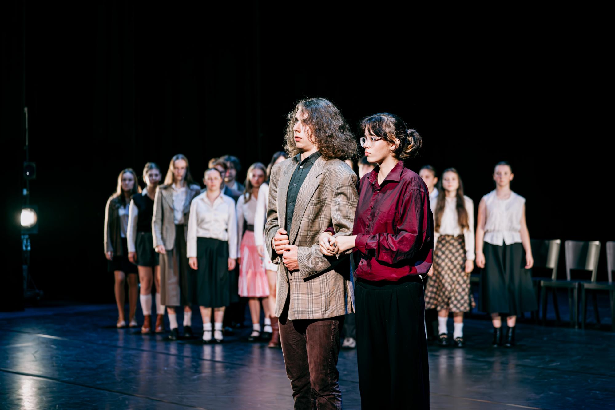 Zwei Personen stehen abseits des Pulks und schauen verunsichert. Der Pulk schaut zu den beiden Personen.