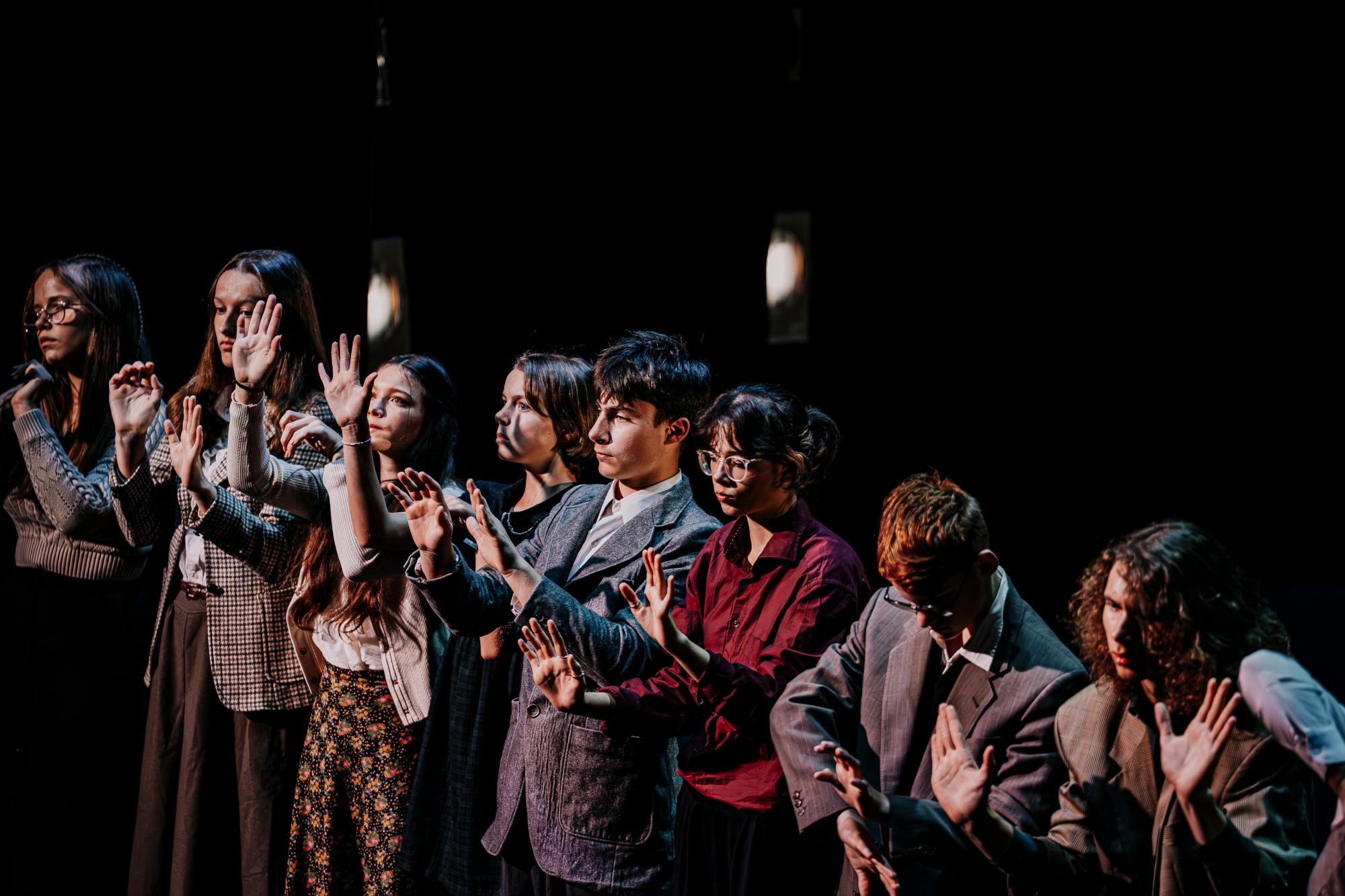 Das Ensemble steht in einer Reihe vor einer imaginären Wand und tastet diese ab.